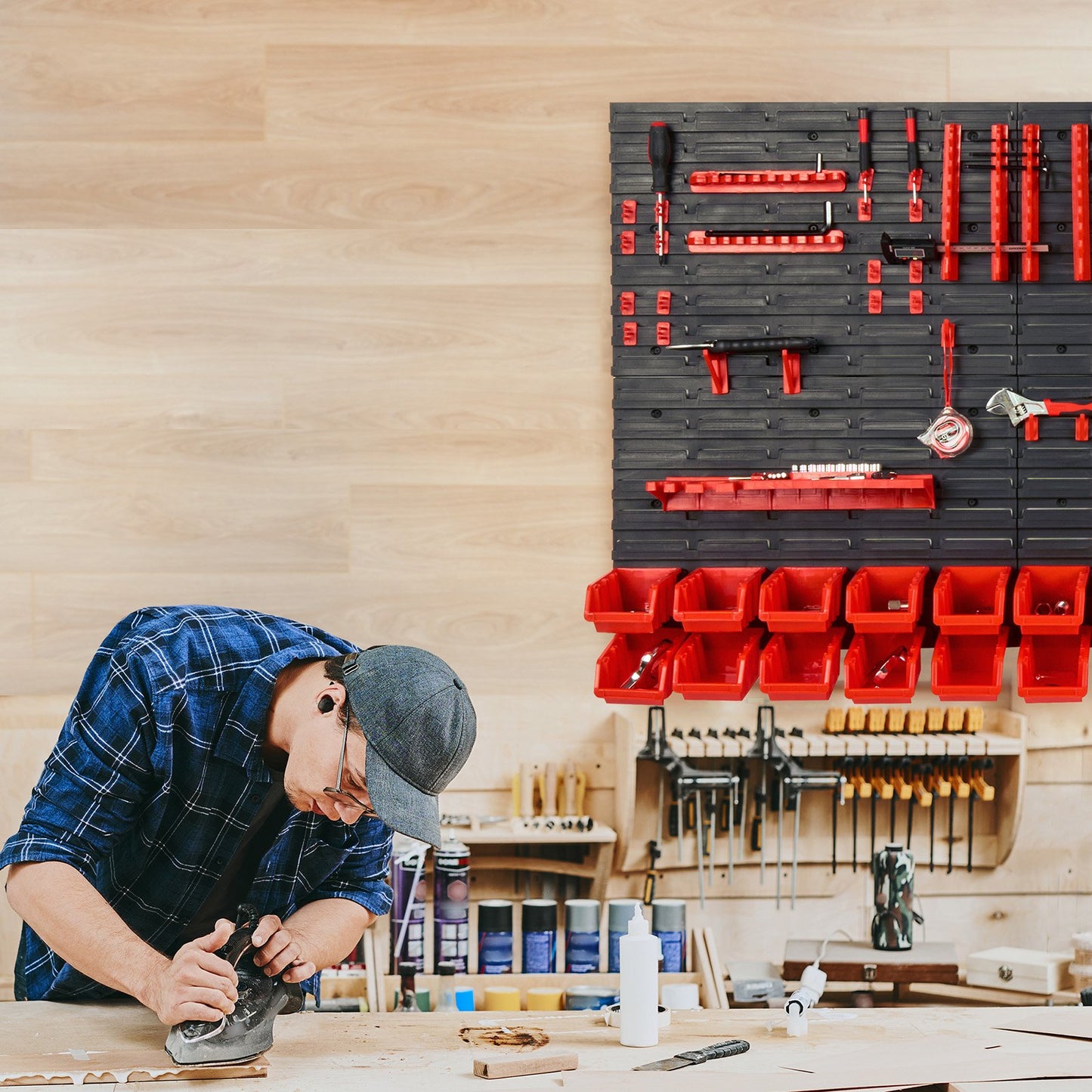 Person working on a project with a wall-mounted tool organizer in a workshop.